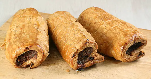 hot pastry sausage rolls on a wooden board