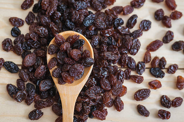 Raisins in a wooden spoon Raisins in a wooden spoon, close-up raisin stock pictures, royalty-free photos & images
