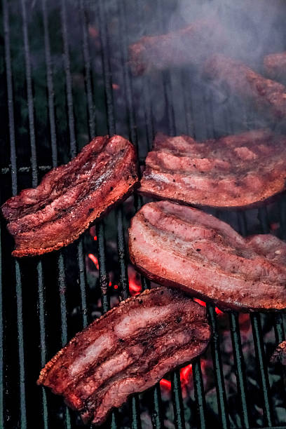 fettine di pancetta grigliata, la produzione di fumo - spit roasted barbecue grill barbecue pork foto e immagini stock