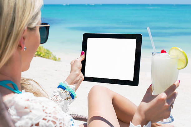 istock Woman drinking cocktail and holding tablet computer on the beach 508543212