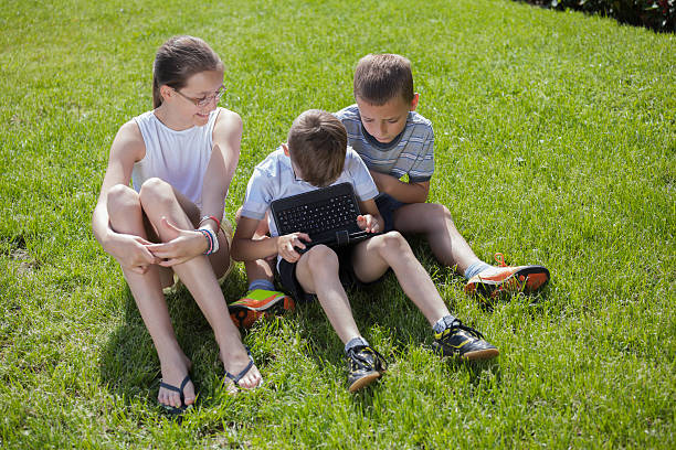 istock Childrens having fun with digital tablet sitting on the grass 508544190