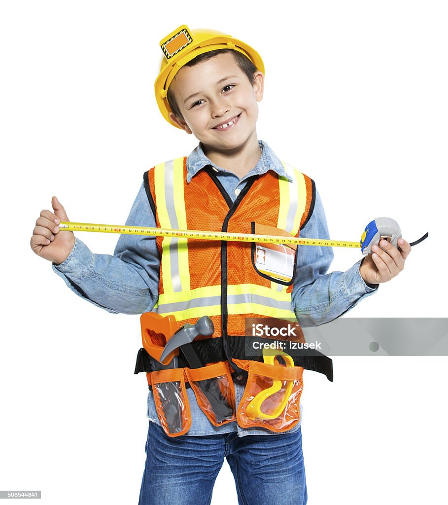 Junior Construction Worker Portrait of little boy dressed as contruction worker, holding tape measure in hands and smiling at camera. Studio shot, isolated on white. Child Stock Photo