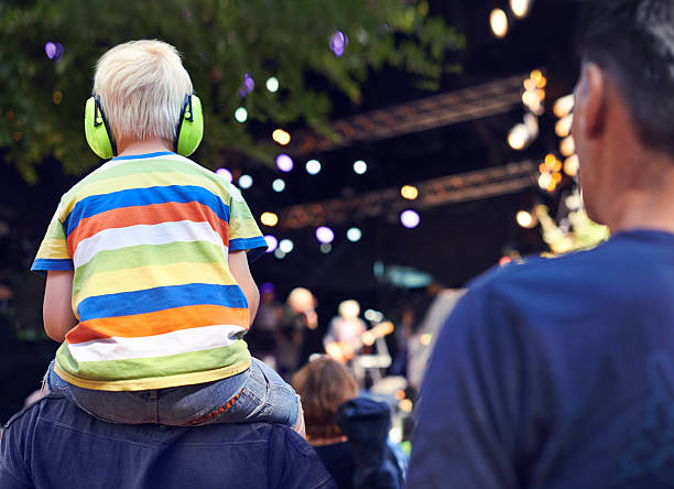 Best seat in the house Rearview shot of a young boy sitting on his father's shoulders at a music concert ear protectors stock pictures, royalty-free photos & images