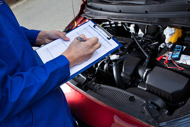 istock Mechanic Holding Clipboard In Front Of Open Car Engine 508545681