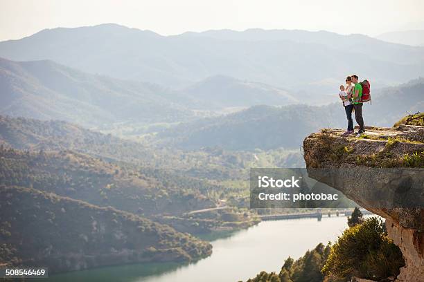 Young Couple With Toddler Boy In Sling Standing On Cliff Stock Photo - Download Image Now