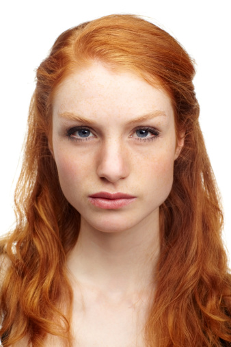 An attractive redhead looking at the camera with a serious expression