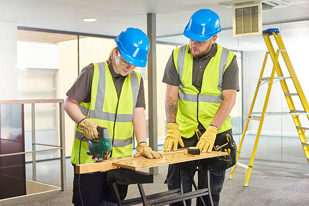 female carpenter apprentice on site a teenage female carpenter is cutting wood on an office refurbishment job helped by her supervisor. She is holding a jigsaw cutter . They are wearing safety workwear. train air conditioner stock pictures, royalty-free photos & images