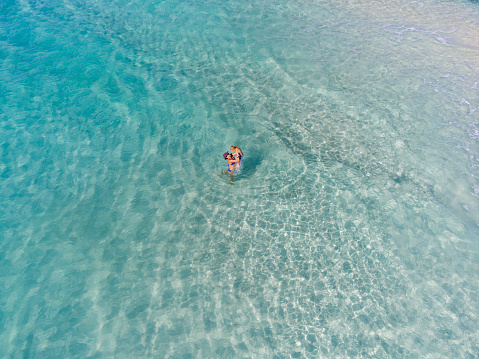 Aerial view of a mother and child playing at a tropical beach in the caribbean