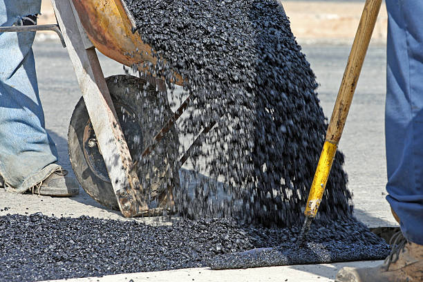 istock Unloading Hot Asphalt From Wheelbarrow On Road repair Site 508555208