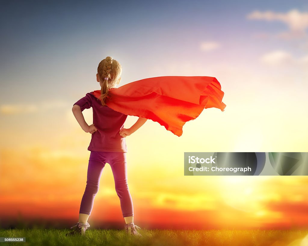 girl plays superhero Little child girl plays superhero. Child on the background of sunset sky. Girl power concept Heroes Stock Photo