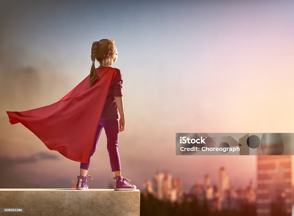 girl plays superhero Little child girl plays superhero. Child on the background of sunset sky. Girl power concept Child Stock Photo