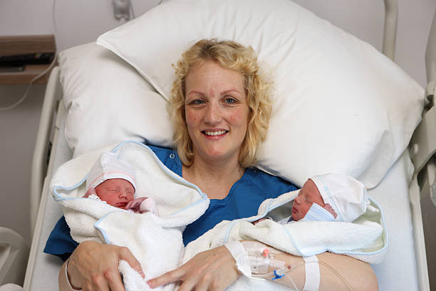 Smiling Mother With Newborn Twins In Hospital stock photo