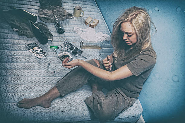 Young Drug Addict A teenage junkie, living in squalor, injecting herself with another hit. Posed by a model. Post-processed for added effect. drug abuse photos stock pictures, royalty-free photos & images