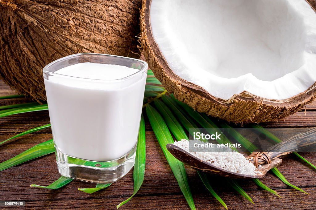 Coconut and coconut milk in glass Coconut and coconut milk in glass on wooden table Backgrounds Stock Photo