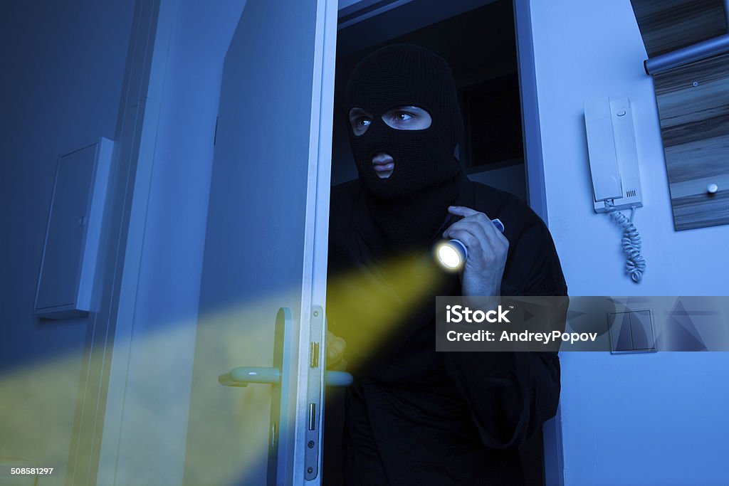 Thief Holding Flashlight While Entering Into House Thief holding flashlight while secretly entering into house Adult Stock Photo