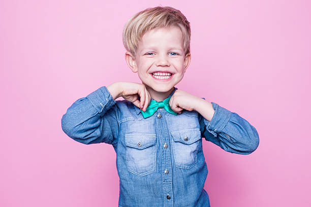 junge schöne lächelnd kind mit blauen hemd und krawatte mit schmetterling - coole jungs frisuren stock-fotos und bilder