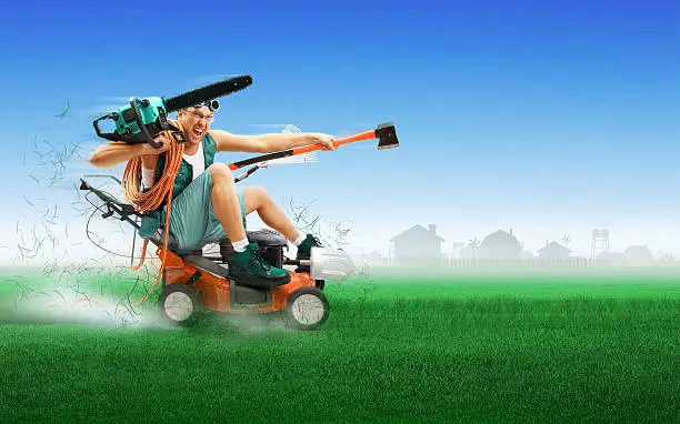 Photo of Crazy workman covered with instruments driving lawn mower
