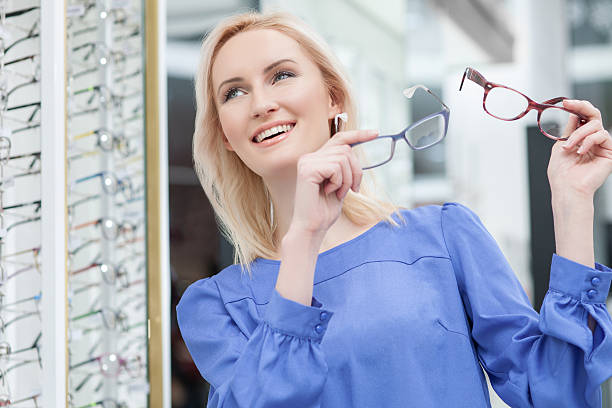 istock Pretty blond girl is choosing glasses in store 508589258
