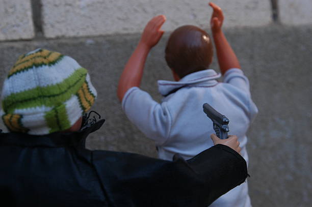 Barbie dolls posed, Man being robbed at gunpoint Provo, Utah, USA - December 4, 2004: Barbie dolls posed outside. Man is being robbed at gunpoint by a thief in a leather jacket. wallet gun stock pictures, royalty-free photos & images