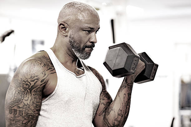 Close up of unrecognizable athletic man taking hand weight from a rack in a gym.