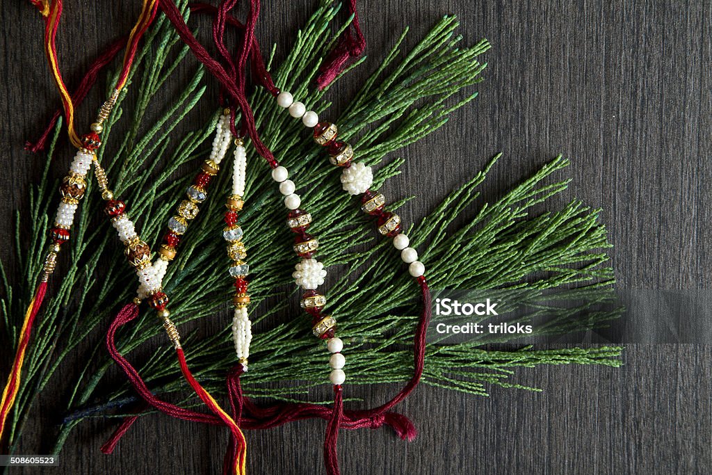 Multi colored Rakhi with plants on wooden table Beautiful Rakhi and Red Rose Anniversary Stock Photo