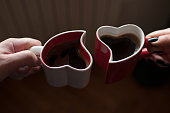 Man and woman holding heart shaped cups with coffee