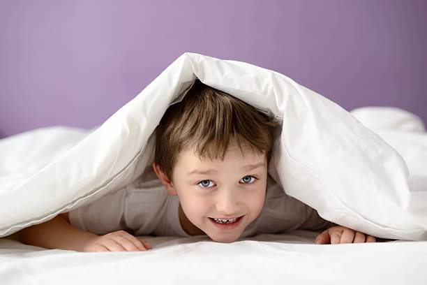 istock Adorable laughing boy playing in bed under a white blanket 508623936
