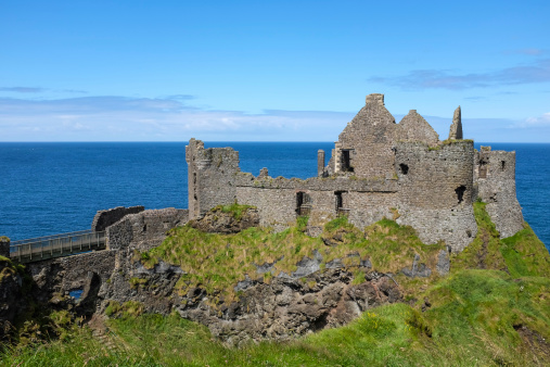 Dunluce Castle is a now-ruined medieval castle in Northern Ireland, the seat of Clan MacDonnell. It is located on the edge of a basalt outcropping in County Antrim (between Portballintrae and Portrush), and is accessible via a bridge connecting it to the mainland. The castle is surrounded by extremely steep drops on either side, which may have been an important factor to the early Christians and Vikings who were drawn to this place where an early Irish fort once stood.