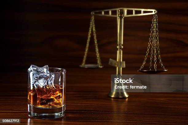 Whiskey And Blurred Scales Of Justice Concept Alcohol And Law Stock Photo - Download Image Now