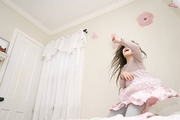 Pretty girl dancing on her bed with high energy An active little girl is dancing on her bed in her bedroom. She's having a lot of fun and is very expressive. air guitar stock pictures, royalty-free photos & images