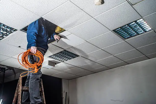 Photo of man looking up the ceiling, checking and repairing