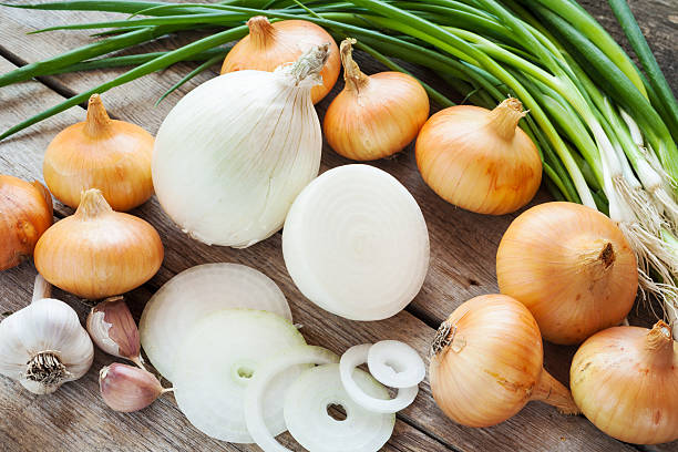 different onions and garlic on wooden table stock photo