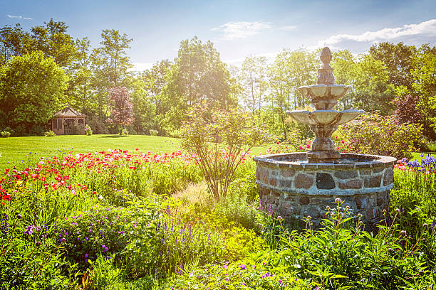 Lush green garden with stone fountain and gazebo in early morning. St. Anne's spa, Grafton, Ontario, Canada.