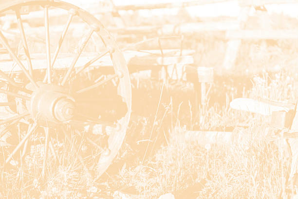 Old-fashioned, vintage wagon in faded sepia tones.  The wagon wheel is in the foreground of this western background.  Wild west themes.  No people.  A relic from the days of the Wild West when real cowboys ruled the land.