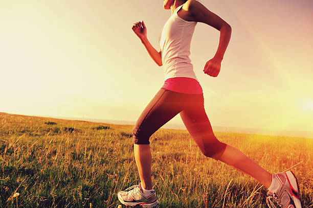 Runner athlete  running on sunrise/sunset grass field. woman fitness jogging workout wellness concept.