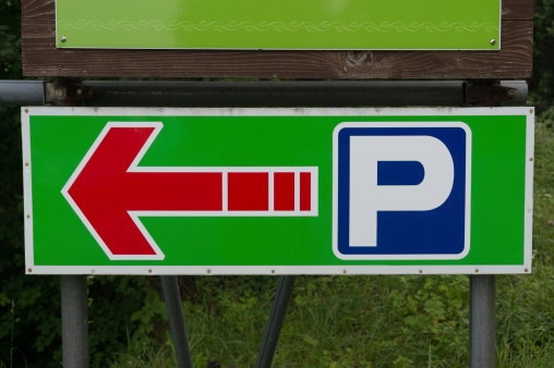 Parking sign direction with red arrow pointing left.
