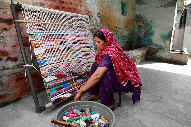Indian woman weaving durries. The durry (Rug) is weaved out of cotton or wool.