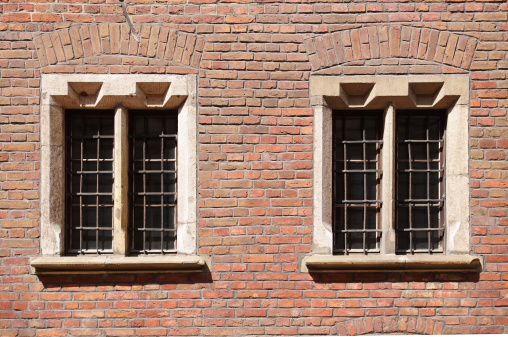 renaissance windows with bars in a red brick wall