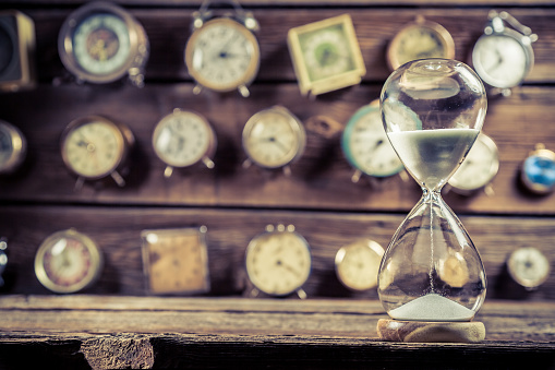 Old hourglass on the background of clocks.