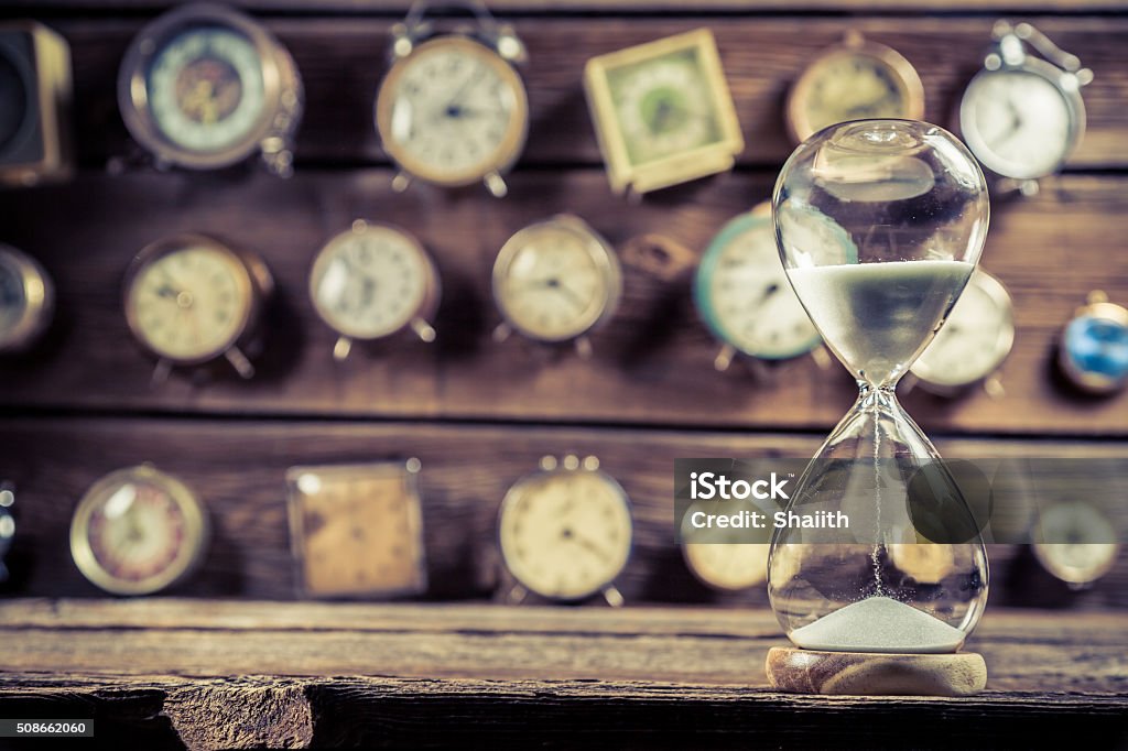 Old hourglass on the background of clocks Old hourglass on the background of clocks. Waiting Stock Photo