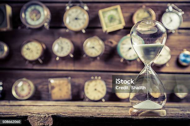 Old Hourglass On The Background Of Clocks Stock Photo - Download Image Now - Waiting, Patience, Sand