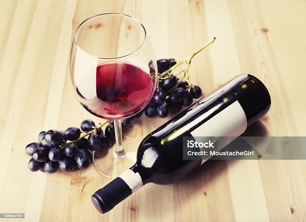 Red wine glass bottle and grapes on wood table Beautiful red wine in the glass and fresh black grapes on the table Abstract Stock Photo