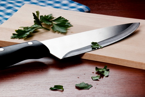 A photo of garlic partially diced on a cutting board, with other vegetables at the side.