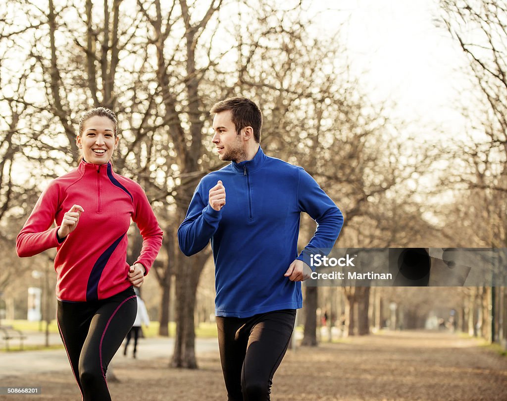 Couple jogging together Young couple jogging together in tree alley - late autumn Active Lifestyle Stock Photo