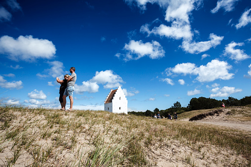 Skagen, Denmark - July 2, 2014: Several groups of tourists are admiring the the sand-buried church south of Skagen and the nature that surounds the chruch.
