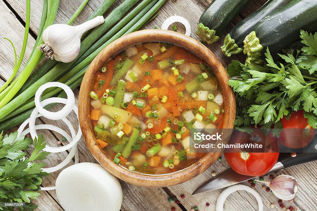 vegetable soup in wooden bowl and ingredients on table vegetable soup in wooden bowl and ingredients on wooden rustic table. top view Above Stock Photo