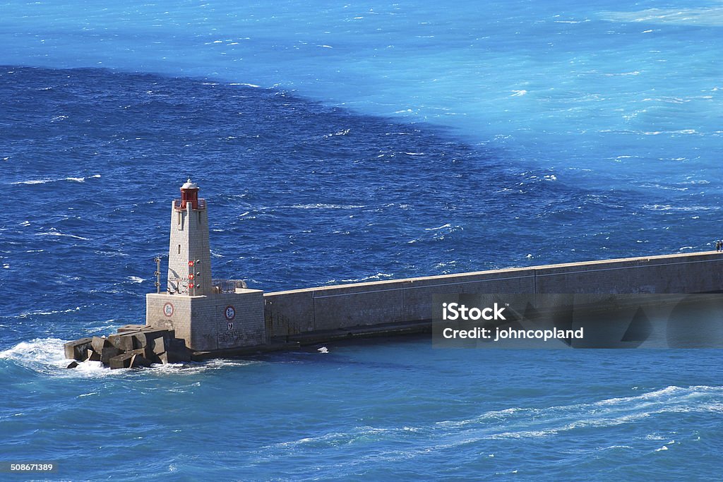 Port entrance and light house, Nice, France. Port entrance,sea wall and light house, surrounded by a beautiful, turquoise, Mediterranean Sea. Nice, France. Alpes-Maritimes Stock Photo