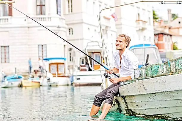 Photo of Business man sitting on edge of the boat, fishing