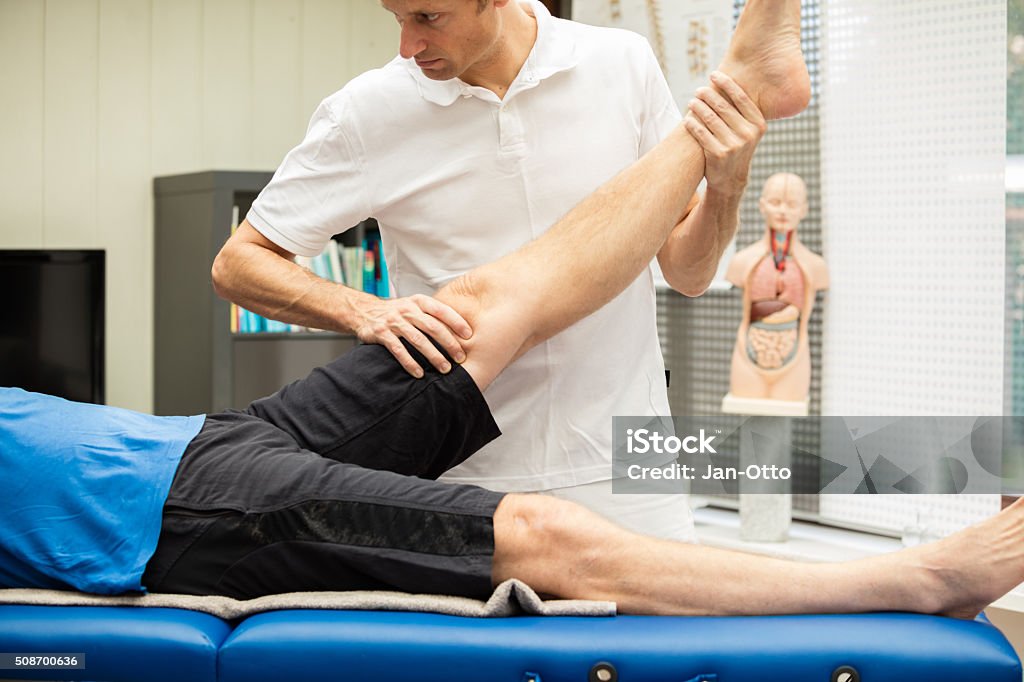 Doctor performing Lasegue test A  doctor, performing Lasegue test at a male patient. This test stretches the nerves of the leg and spine and gives information about the origin of pain. Human Spine Stock Photo