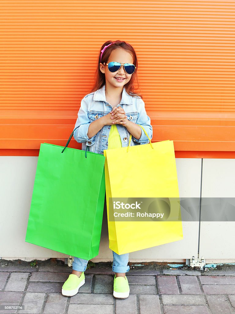 Happy little girl child with shopping bags in city Happy little girl child wearing a sunglasses and jeans clothes with shopping bags in city Arts Culture and Entertainment Stock Photo